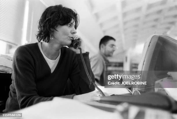 La journaliste Florence Aubenas téléphone, le 09 juillet 2001 à Paris, depuis son poste de travail au sein de la rédaction du journal Libération. AFP...