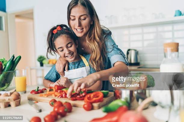 mère et descendant coupant des légumes pour une salade ensemble - mother and daughter cooking photos et images de collection