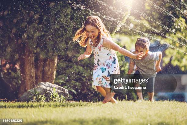 glückliche kinder spielen mit garten sprinkler - garden stock-fotos und bilder