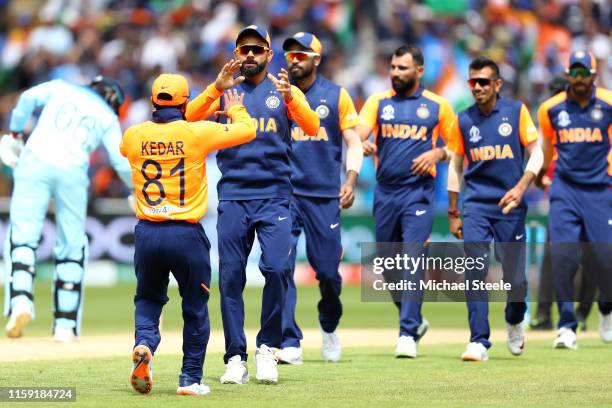 Virat Kohli the captain of India applauds Kedar Jadhav after taking a catch off the bowling of Mohammed Shami to dismiss Eoin Morgan during the Group...