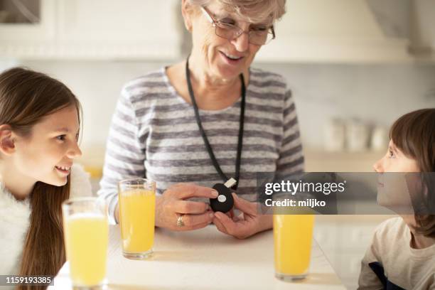 senior woman showing panic button device to her grandchildren in living room - panic button imagens e fotografias de stock