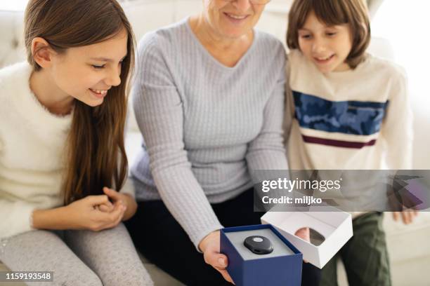 senior woman showing panic button device to her grandchildren in living room - panic button imagens e fotografias de stock