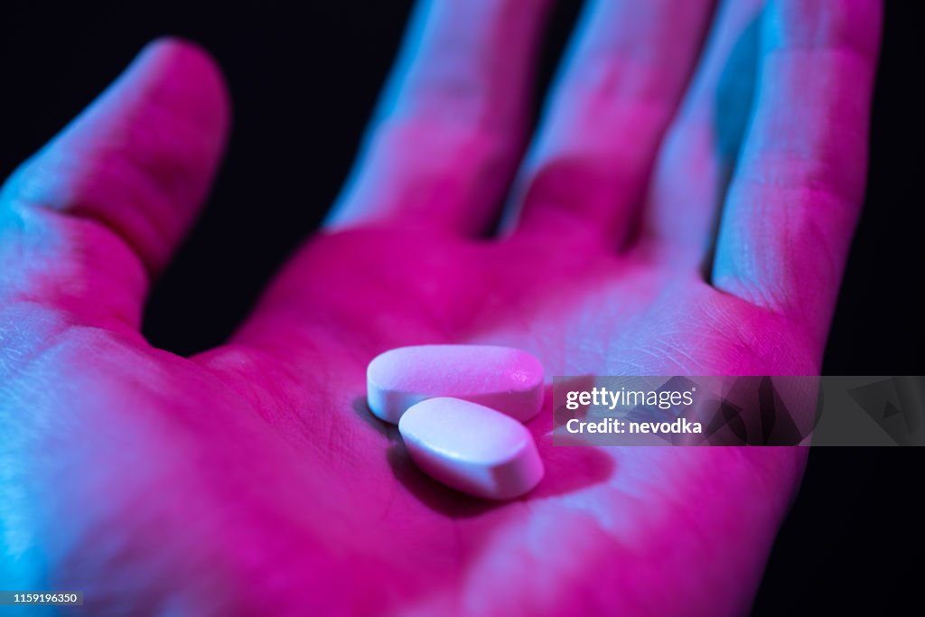 Pills in hand. Two drug tablets in palm