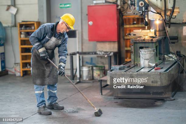 pulizia dello sporco industriale da parte dei lavoratori - sweeping foto e immagini stock