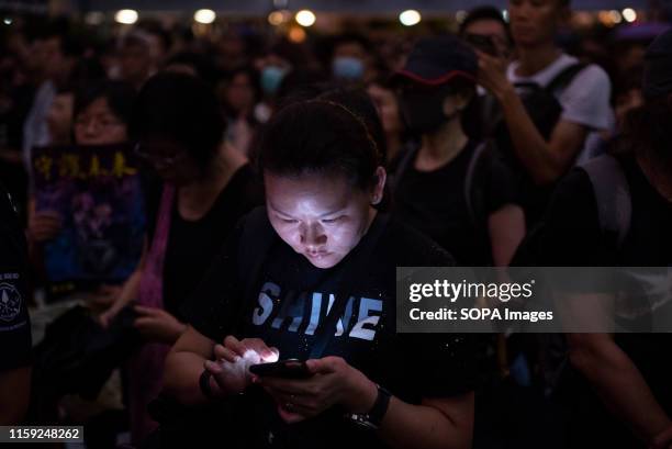 Protester uses her smartphone during the rally. People gathered for a demonstration by civil servants at Chater Garden in the financial district of...