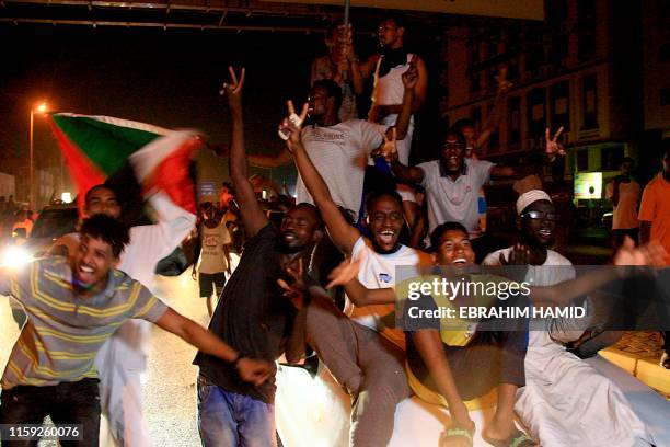 Sudanese demonstraters wave their national flag as they celebrate in Khartoum early on August 3 after Sudan's ruling generals and protest leaders...