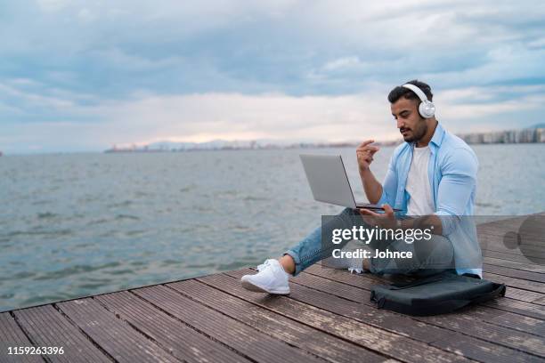 knappe man geniet van muziek aan zee - met de vingers knippen stockfoto's en -beelden