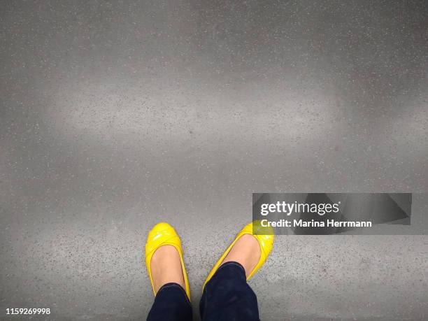 lower section of female legs on gray floor - schuhe von oben stock-fotos und bilder