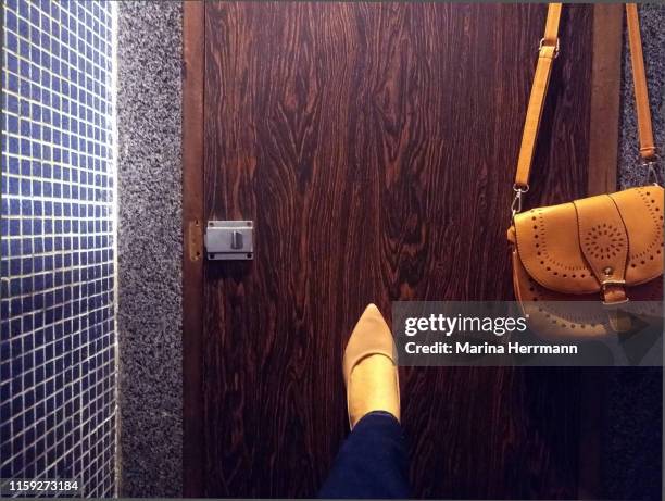 woman holding the toilet door with her foot - public restroom door stock pictures, royalty-free photos & images