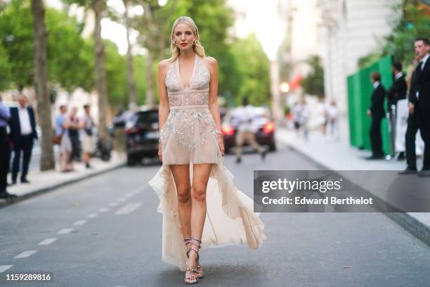 Leonnie Hanne wears earrings, a low neck lace dress with sequined inserts, heels shoes, outside AMFAR dinner, during Paris Fashion Week - Haute...