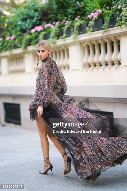 Caroline Daur wears a ruffled lace dress with snake print and black mesh, a black bag, earrings outside AMFAR dinner, during Paris Fashion Week -...