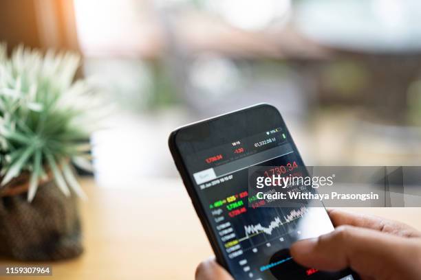 businessman using a mobile phone to check stock market data - aandelen beurs stockfoto's en -beelden