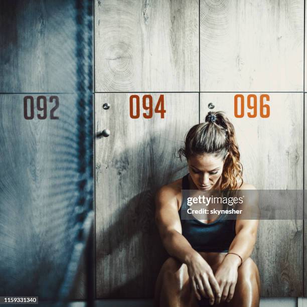 müde sportlerin ruht auf einer pause in der umkleidekabine des fitnessstudios. - künstlergarderobe stock-fotos und bilder