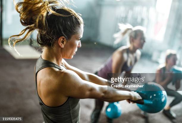 sportliche frau, die mit einer klasse in einem fitnesscenter mit kesselglocke trainiert. - sports training stock-fotos und bilder