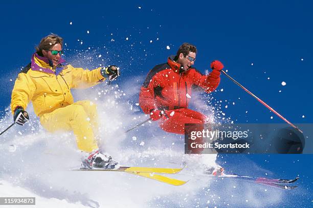 dos skiers salto de nieve con cielo azul - mogul skiing fotografías e imágenes de stock