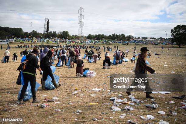 Festival-goer walks through a clean-up crew as it clear litter and debris from the area in front of the Pyramid Stage on the morning after the final...