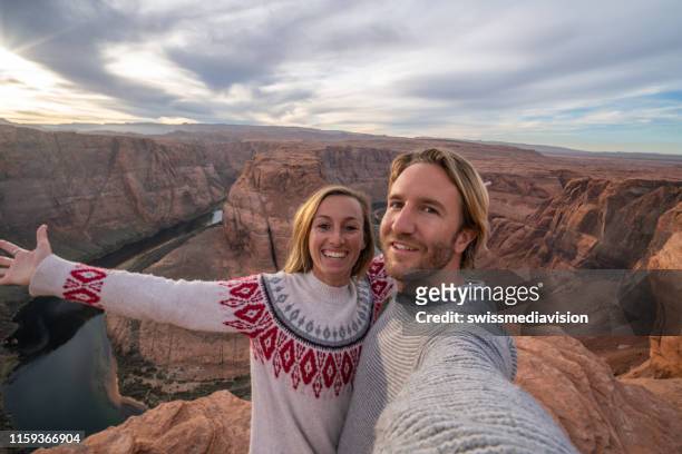 young couple traveling in usa taking a selfie by the famous horseshoe bend river - couple grand canyon stock pictures, royalty-free photos & images