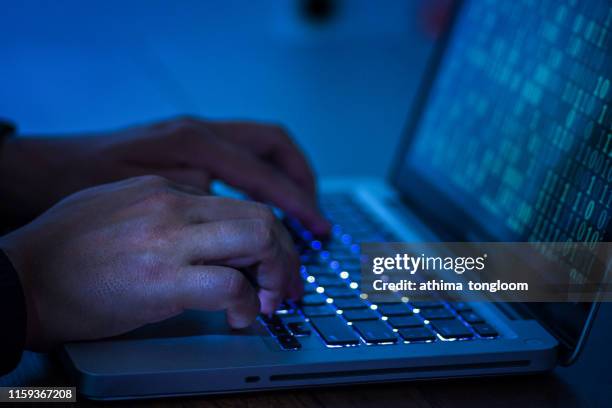 a computer programmer or hacker prints a code on a laptop keyboard to break into a secret organization system. - stealing crime stock pictures, royalty-free photos & images