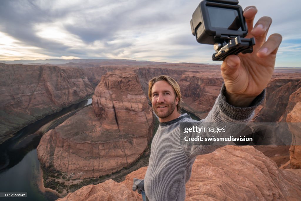 Young man taking selfie with action camera at the horseshoe bend in Arizona, USA