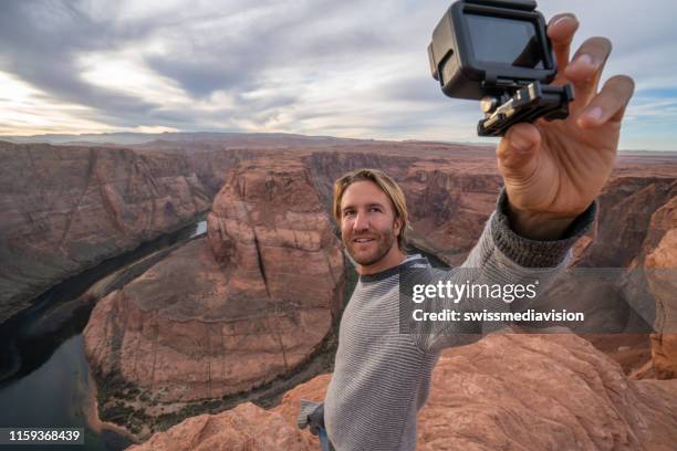 young man taking selfie with action camera at the horseshoe bend in arizona, usa - action camera stock pictures, royalty-free photos & images