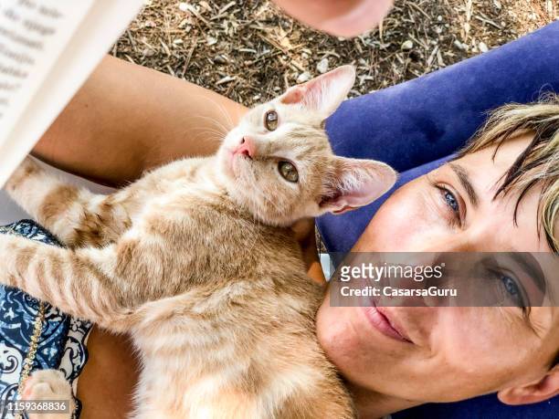 carefree adult woman relaxing with her cat outdoors - cat selfie stock pictures, royalty-free photos & images