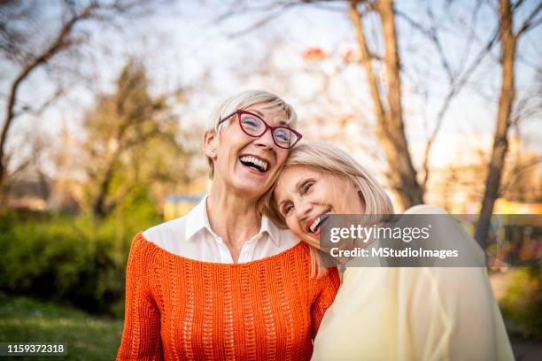 zwei seniorinnen lachen im park - siblings stock-fotos und bilder