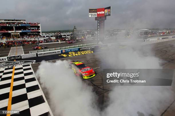 Jeff Gordon, driver of the DuPont Chevrolet, performs a burnt out to celebrate winning the NASCAR Sprint Cup Series 5-Hour Energy 500 at Pocono...