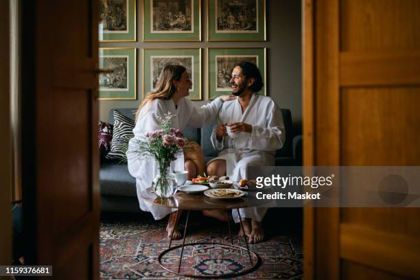 happy couple in bathrobes in hotel room - hotel stock-fotos und bilder