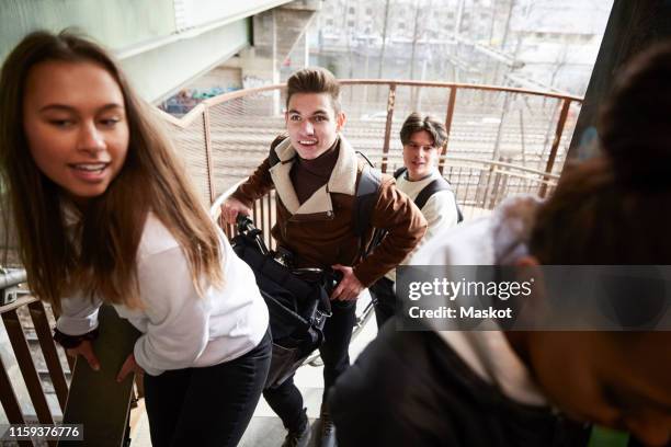 male and female teenage friends carrying bicycle and electric push scooter on staircase - girl rising stock pictures, royalty-free photos & images