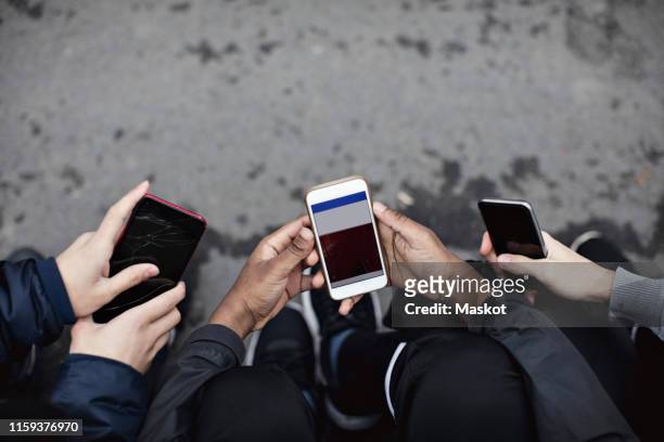 high angle view of friends using social media in mobile phone on street - 3 teenagers mobile outdoors stock-fotos und bilder