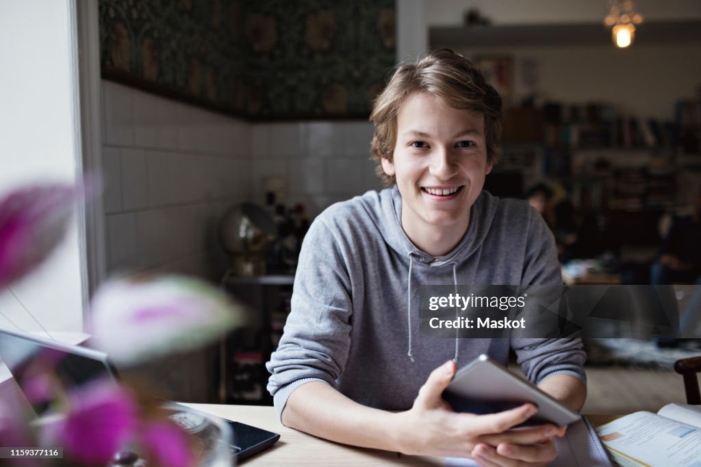 Portrait of smiling teenage boy studying at home