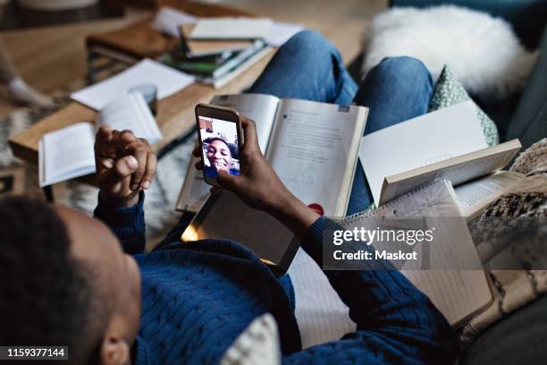 high angle view of happy teenage boy taking selfie while studying in living room at home - distrarsi foto e immagini stock