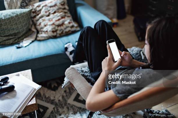 high angle view of boy using mobile phone while sitting in living room - smart phone angle stock pictures, royalty-free photos & images