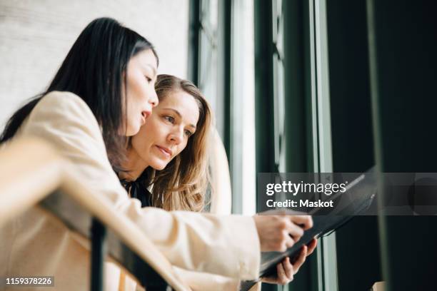 low angle view of businesswoman discussing with colleague over document at office - international day two stock pictures, royalty-free photos & images