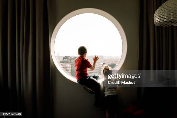 siblings by window in hotel room - two people looking at view stock pictures, royalty-free photos & images