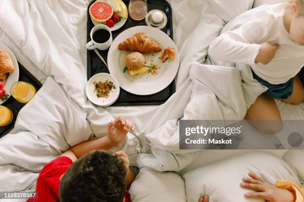 directly above shot of family having breakfast on bed in hotel - hotel breakfast stock pictures, royalty-free photos & images