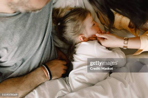 directly above shot of girl sleeping with parents in bed at hotel - kids hotel bildbanksfoton och bilder