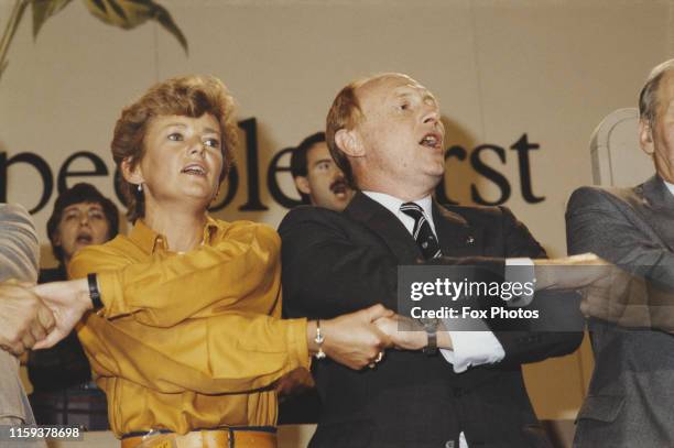 British politician Neil Kinnock, Leader of the Labour Party, singing 'Auld Lang Syne' with his wife Glenys at the Labour Party Conference in...