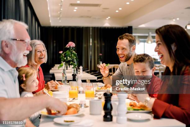 cheerful family talking while having food at table in restaurant - children restaurant stockfoto's en -beelden