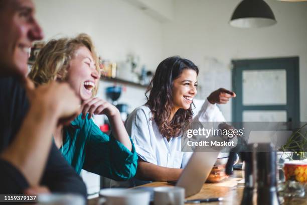 confident cheerful it professionals sitting at table while working in creative office - coffee break office stock-fotos und bilder