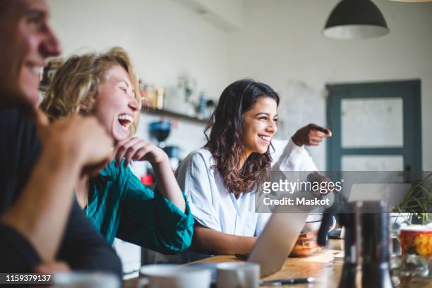 confident cheerful it professionals sitting at table while working in creative office - pause café bureau photos et images de collection