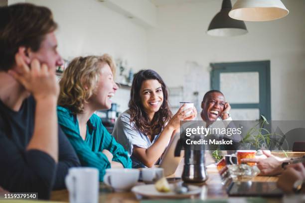 portrait of cheerful young female computer programmer sitting with hackers at table in creative office - happy programmer stock pictures, royalty-free photos & images