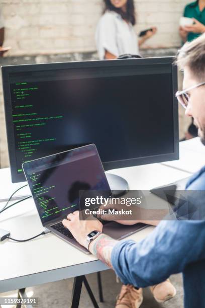 male computer programmer coding in laptop while working at desk in office - business casual dress code stock pictures, royalty-free photos & images