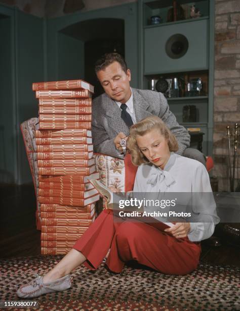 Married American actors Dick Powell and June Allyson reading a new set of the 'Encyclopaedia Britannica', USA, circa 1947.