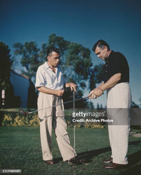 American television personality Ed Sullivan plays golf with actor Clark Gable , circa 1950.