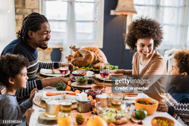 happy afro-amerikaanse familie communiceren terwijl het hebben van thanksgiving lunch in de eetzaal. - thanksgiving table stockfoto's en -beelden