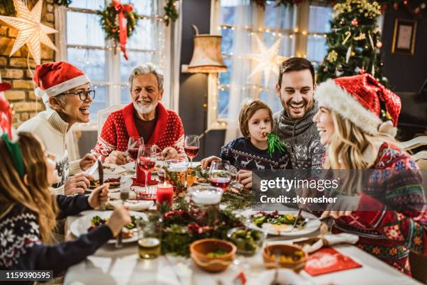 feliz familia extendida que tiene el almuerzo de año nuevo en la mesa de comedor. - eating food fotografías e imágenes de stock