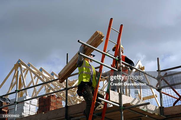 low view of two construction workers on top of house frame - construction lift worker stock pictures, royalty-free photos & images