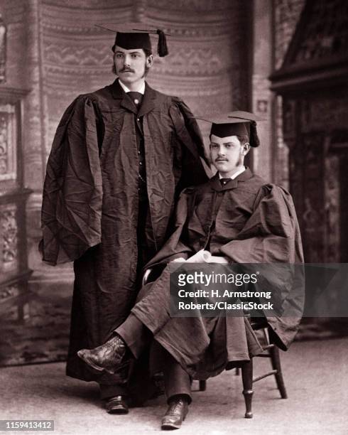1890s 1900s TWO MEN COLLEGE UNIVERSITY GRADS GRADUATES POSING IN CAPS AND GOWNS