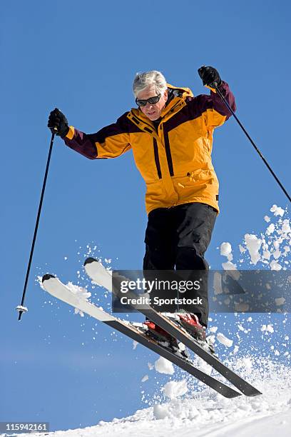 senior man jumping on snow skis - senior winter sport stock pictures, royalty-free photos & images